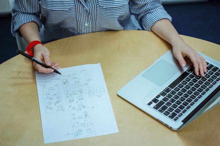 Student answering an AI-generated question on paper beside a laptop