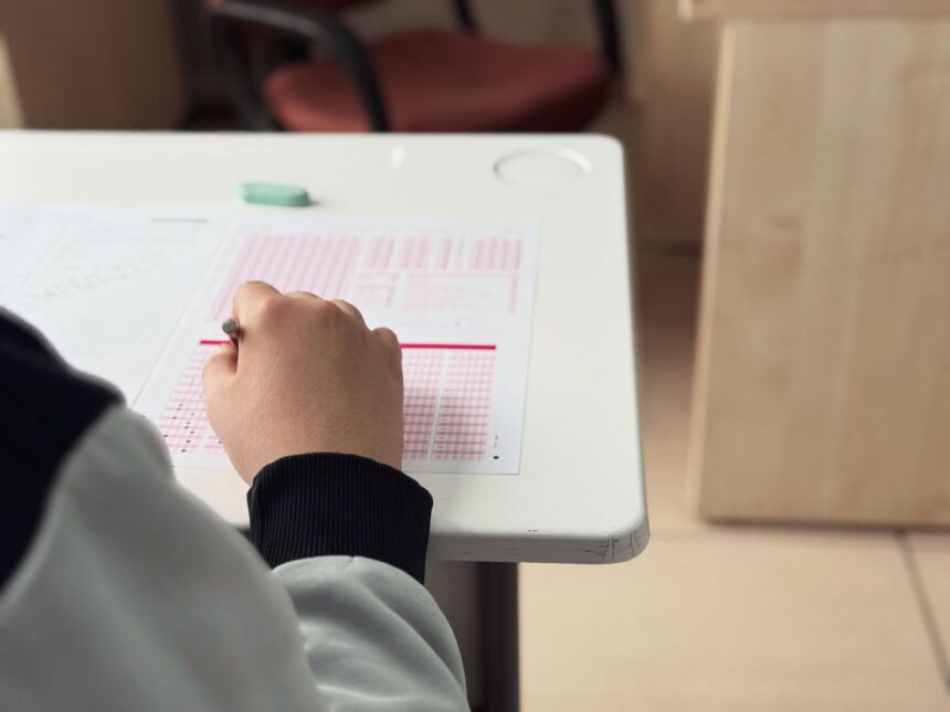 Student practicing active recall on paper next to a laptop displaying an AI-generated quiz